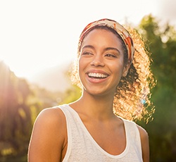 A young woman smiling with a sunset in the background