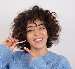 a patient smiling and holding her Invisalign tray