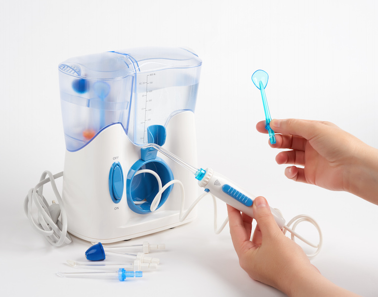 Person uses oral irrigator Lovell Dental Blog